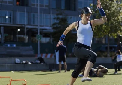 A woman running agility drills on a city park field